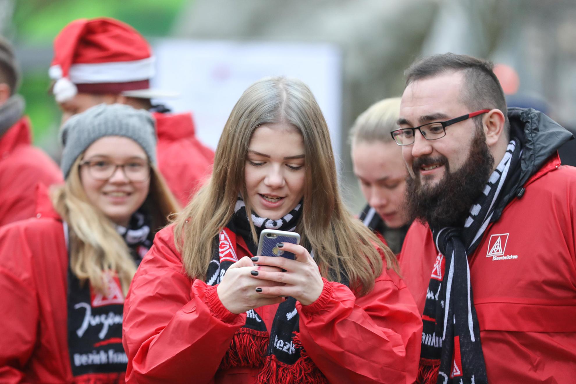 Junge Frau tippt in ihr Handy. Ein Junger Mann schaut mit auf das Gerät.